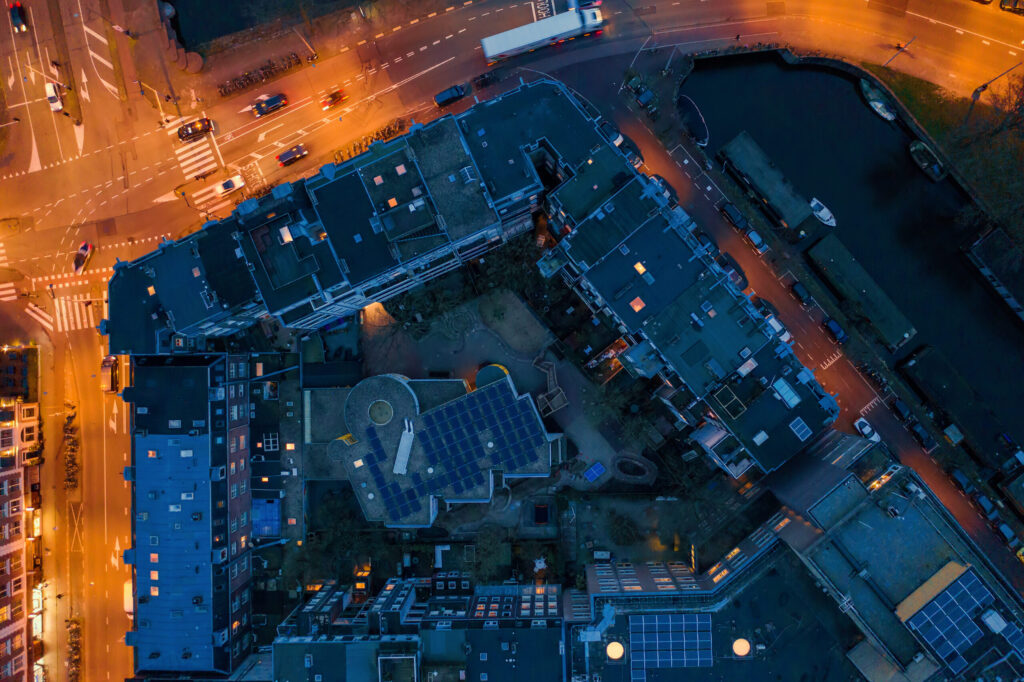 Dronefoto van een nederlandse stad in de avond met daken van gebouwen en wegen.